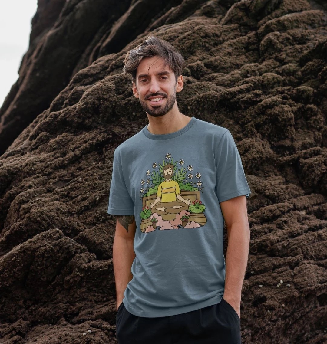 Model wearing a light blue t-shirt with an illustration across the chest. The illustration features a person in a meditation pose surrounded by plants.